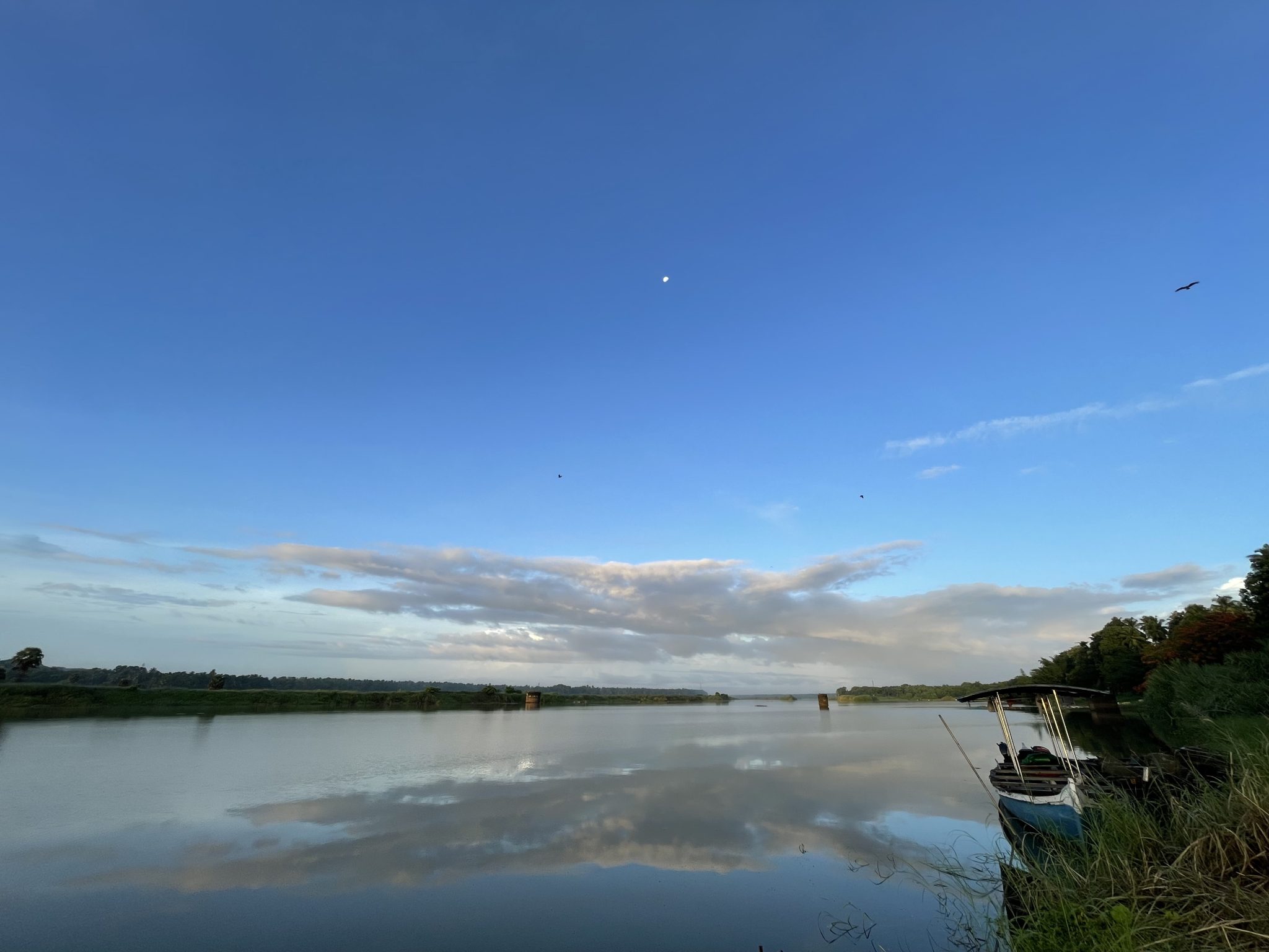 Moon, river, clouds & an abandoned boat just before sunrise. From the banks of Bharathappuzha aka Nila River. Near to Thirunavaya Sree Nava Mukunda Temple, Malappuram, Kerala.