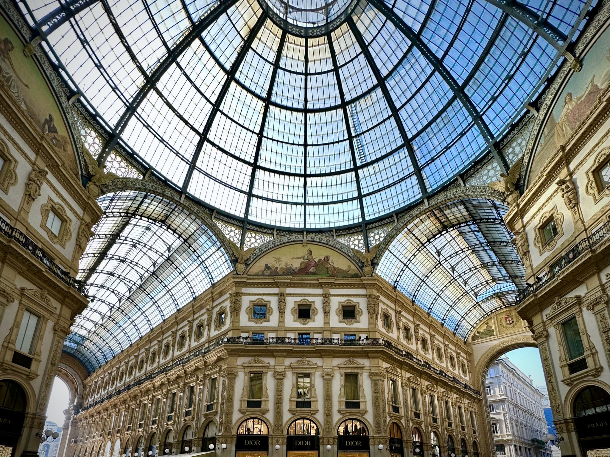 "Galleria Vittorio Emanuele II" in Milan seen from the inside of the arcade. The walls are lavishly decorated with stucco, frescoes and marble.
