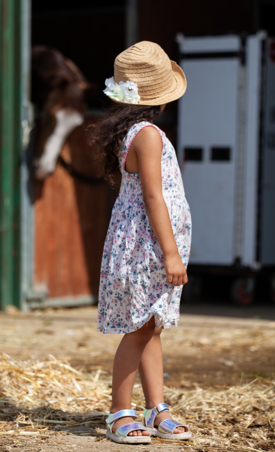child in hat looking at horse